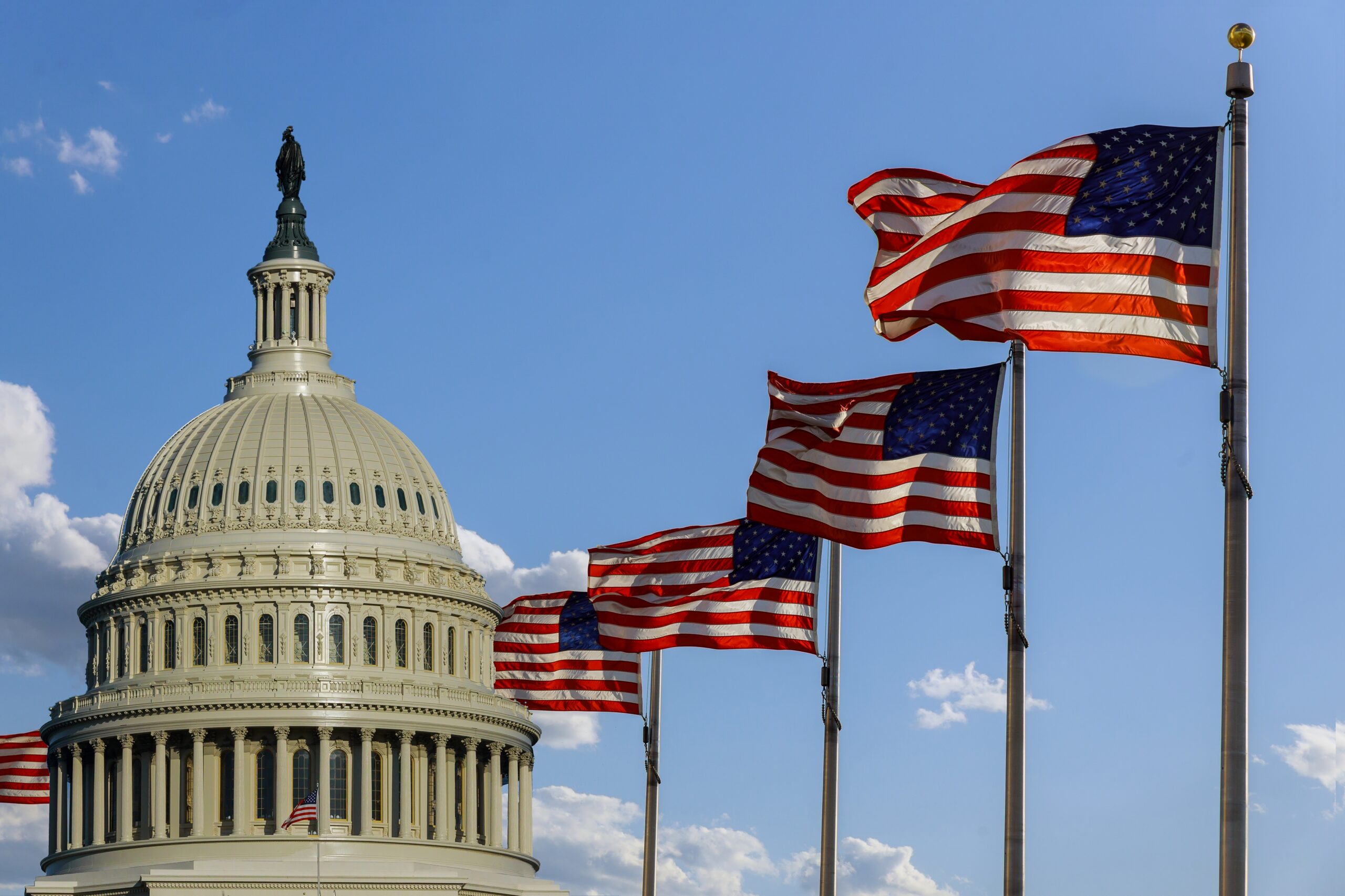 Capitol building in Washington, DC with United States flags on the sky
